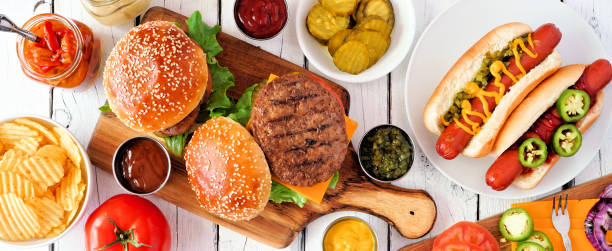 летний барбекю пищевой стол сцены с хот-дог и гамбургер шведский стол, сверху вниз вид баннер над белым деревом - hot dog hamburger burger grilled стоковые фото и изображения