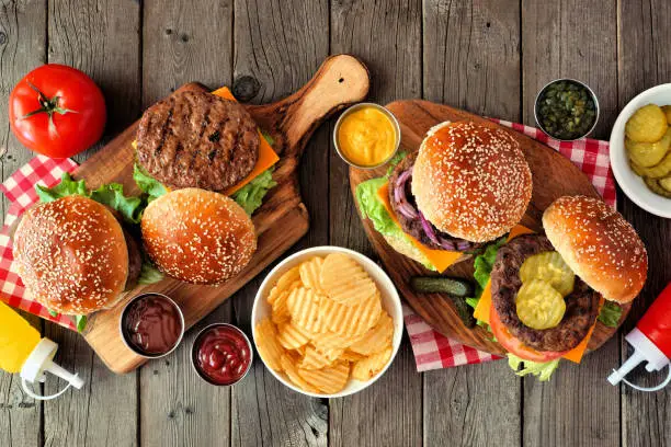 Photo of BBQ hamburger table scene, top view over dark wood