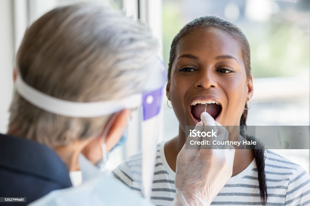 Woman opens mouth for cheek and throat swab while being tested for Covid-19 coronavirus Medical Test Stock Photo