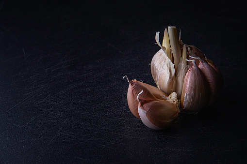 Big and small heads of garlic on a black background.