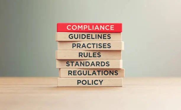 Photo of Compliance Related Words Written Wood Blocks Sitting on Wood Surface in Front a Defocused Background