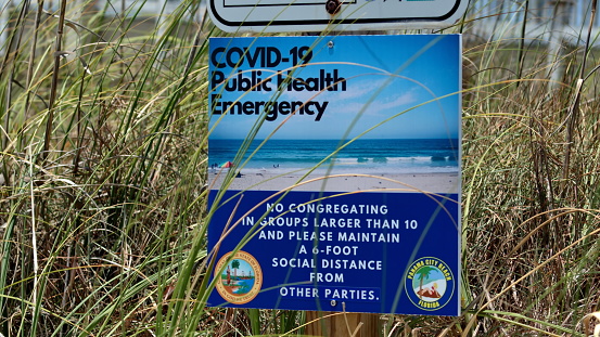 Caswell Beach, NC, USA - September 27, 2015: View of the Atlantic Ocean coast beach with dunes and warning signs about no lifeguard and rip currents in the foreground