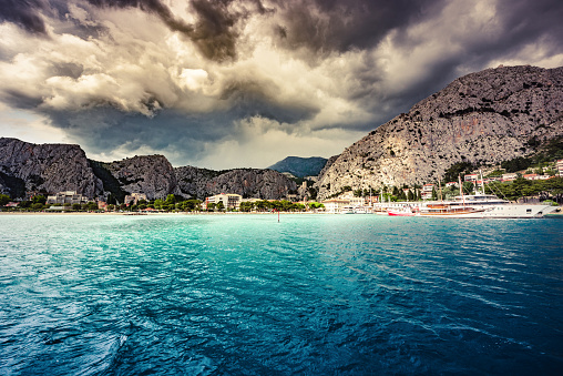 Town of Omiš in Croatia and rocky cliffs with dramatic sky.