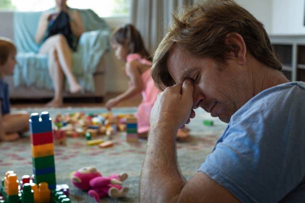 depressed stressed out father at home with his kids and wife. - debt crisis fotos imagens e fotografias de stock