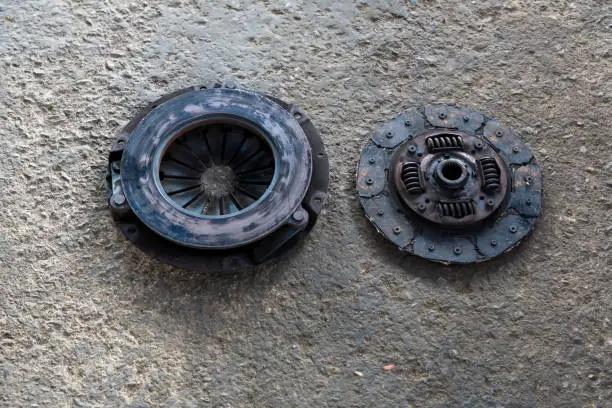 Old Disc Clutch and cover on floor. Old rusty clutch and the disc lies in the garage. Car rusty clutch pressure plate assembly  with clutch disc plate and fly wheel
