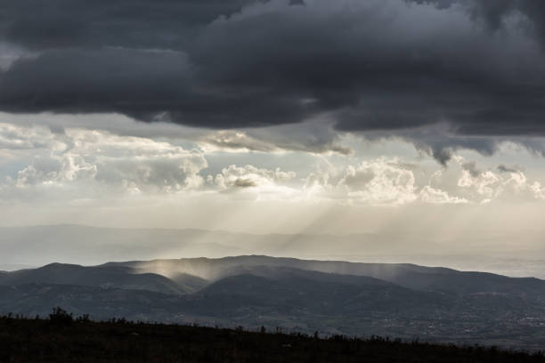 istock Sunrays coming over mountains beneath moody clouds 1252832918