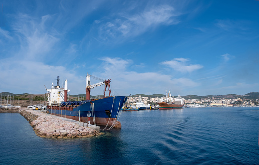 Old oil tanker moored at harbor. Ships anchored at port, city of Laurium blue calm sea and cloudy sky background. Attica, Greece.
