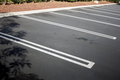 A view of a newly paved parking featuring empty parking stalls.