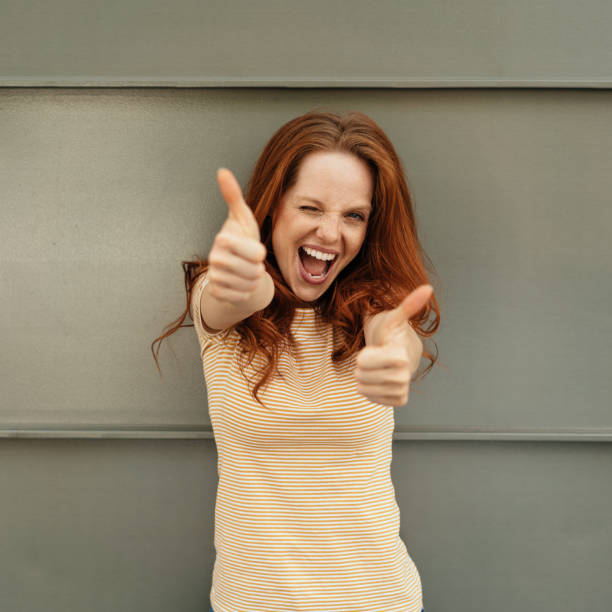 istock Exuberant young woman giving a double thumbs up 1252838273