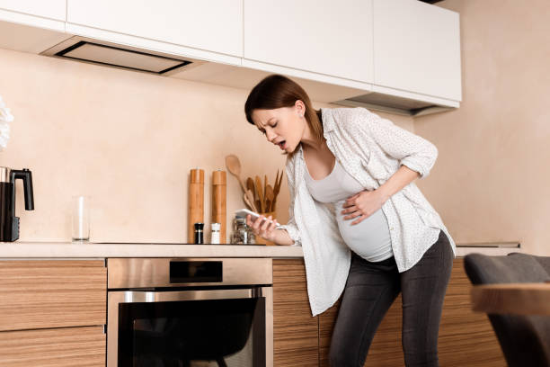 istock pregnant woman touching belly and having cramp while holding smartphone in kitchen 1252842003