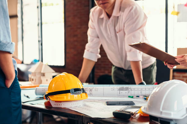 istock safety helmets  on the table at site construction. Architect, Engineer and businessman  read  planning background. 1252845379