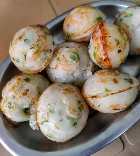 Photo of close up of plate full of south Indian snack made by steaming batter is known by various names, including paddu, appe, guliappa, gulittu, yeriyappa, gundponglu, ponganalu. selective focus.