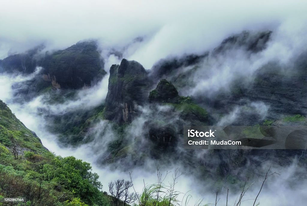 Mountain cliff with greenery and clouds during monsoon season at Tamhini Ghat viewpoint Maharashtra. Western ghats at the start of monsoon season. Western Ghats Stock Photo