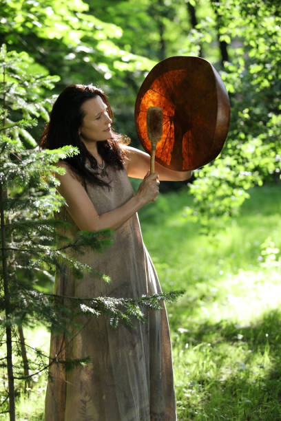 Female shaman doing ritual of summoning spirits Female shaman doing authentic ritual of summoning spirits with a tambourine at sunset in the forest summoning stock pictures, royalty-free photos & images