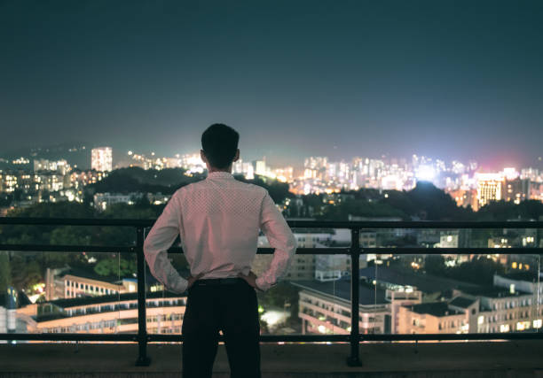 istock Businessman standing rooftop looking city night 1252849473