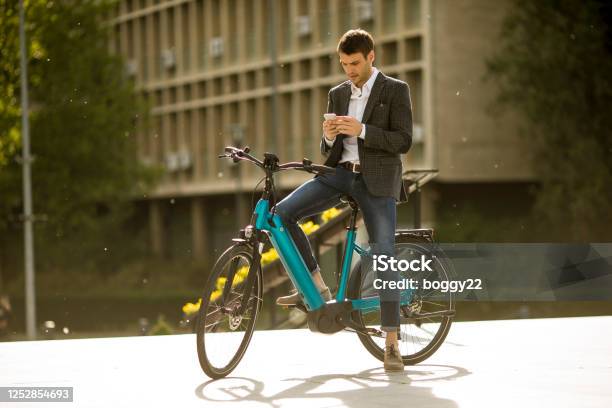 Young Businessman On The Ebike Using Mobile Phone Stock Photo - Download Image Now - Electric Bicycle, Cycling, Bicycle