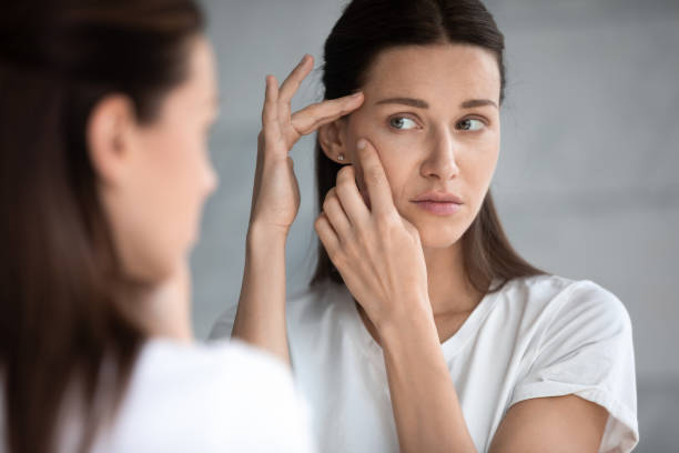 Anxious young woman look in mirror worried about face acne Anxious young woman look in the mirror worried about wrinkle or acne on unhealthy skin, upset unhappy millennial female examine squeeze pimple on face, cosmetology, skincare concept wrinkled stock pictures, royalty-free photos & images