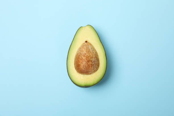 istock Half of fresh avocado on blue background, space for text 1252856876