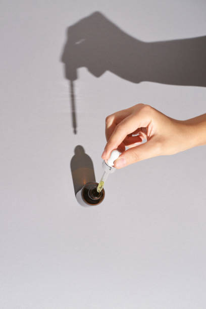 istock Woman hand hold serum dropper. Hard shadow 1252859831