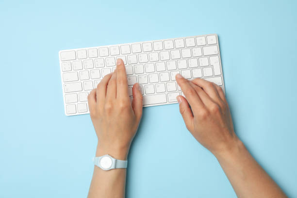 istock Female hands with clock are typing on the keyboard on blue background 1252860928