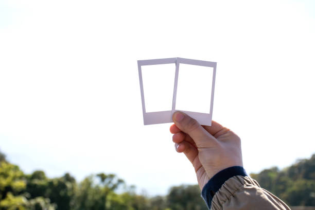 istock Woman hand holding white picture frame with nature blurred background. Clipping path include inside picture frame. 1252865515