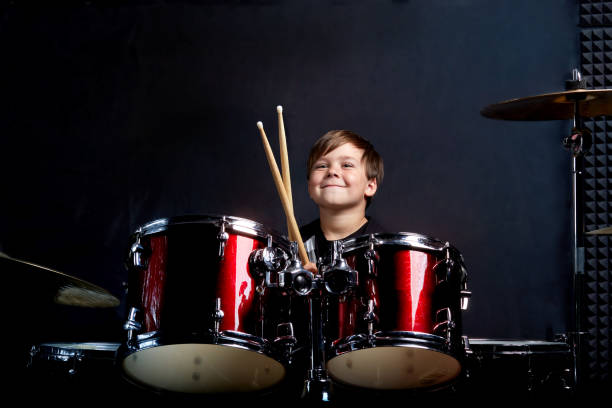 istock The child sits with drumsticks in his hands. Studying in the studio. 1252866440
