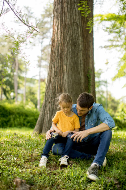 istock Single father sitting on grass by the tree with little daughter 1252867851