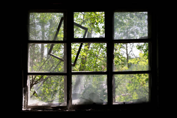 istock A broken window in an abandoned building. Daylight coming through the broken window of an old abandoned room. Greenery outside the window. Ruins. 1252869034