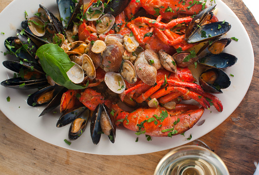 Lobster with Seafood stew or bouillabaisse. Classic Italian or French restaurant seafood entree. Made with lobster, scallops, mussels, razor clams, shrimp, octopus and squid sautéed in garlic, onions, butter and olive oil.