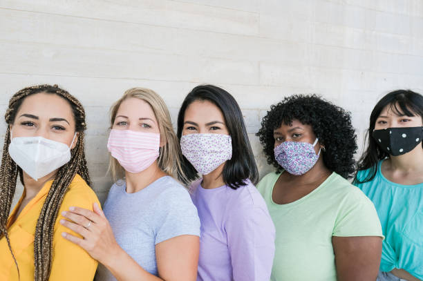istock Young beautiful multiracial women standing in a queue and wearing protective face masks - Happy women smiling - Different skin color, love and stop racism 1252876151