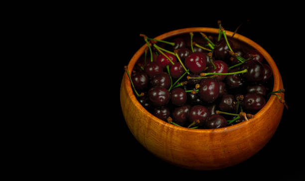 istock Cherry in a wooden bowl on a black background 1252876184