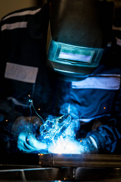 istock Man dressed in protective suit welding metal doors 1252877986