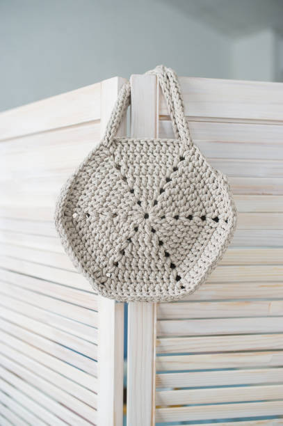 istock Empty gray knitted bag hanging on wooden door. 1252882062