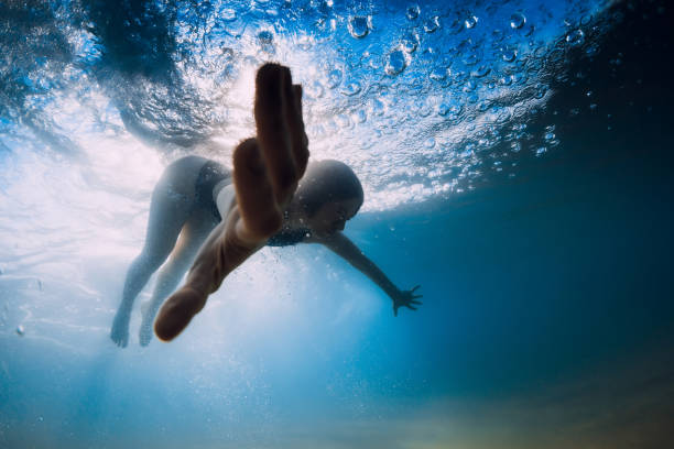 istock Woman dive without surfboard under ocean wave. Underwater duck dive under wave and sandy bottom 1252883044