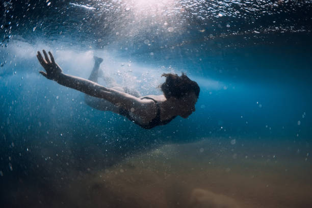 istock Woman dive without surfboard under ocean wave. Underwater duck dive under wave and sandy bottom 1252883114