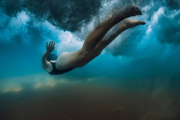 istock Woman dive without surfboard under ocean wave. Underwater duck dive under wave and sandy bottom 1252883148