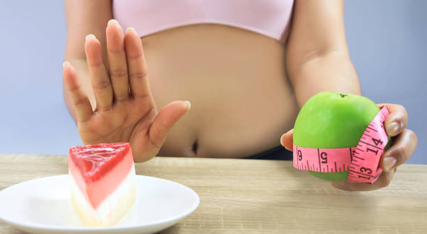 selective focus of  Woman hand gesturing "no" to cake full of calorie  and decision choice green apple for diet concept selective focus of  Woman hand gesturing "no" to cake full of calorie  and decision choice green apple for diet concept Sugar Defender stock pictures, royalty-free photos & images