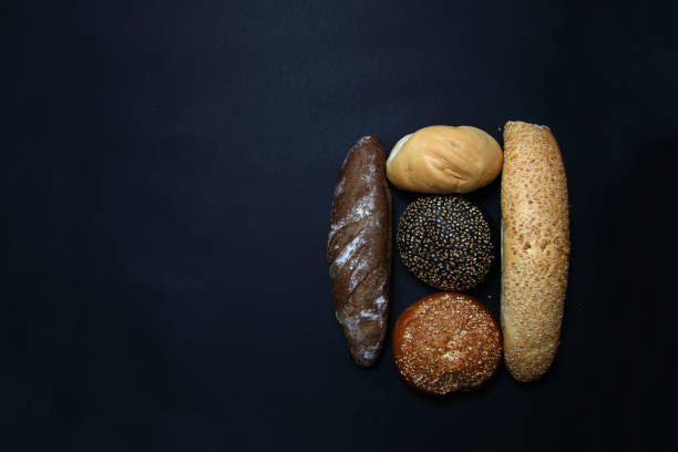 two baguettes and three scones isolated on black background flat lay