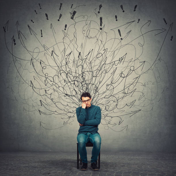 Pessimistic, disappointed and depressed businessman keeps hand under cheek, seated on a chair as mess curves comes out of him like negative energy. Dissatisfied person suffers a midlife crisis. un hombre de negocios pesimista, decepcionado y deprimido mantiene la mano bajo la mejilla, sentado en una silla mientras las curvas desordenadas salen de él como energía negativa. la persona insatisfecho sufre una crisis de mediana edad.