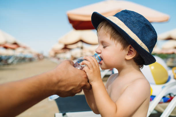 istock Child drinking water on the beach on summer vacations 1252890028