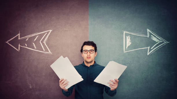 istock Perplexed businessman has to choose as holds different paper documents in both hands. Selecting the correct financial report, arrows shows left and right sides. Difficult decision, doubt concept. 1252890963