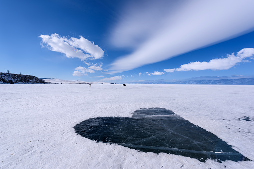 Frozen Lake Baikal covered with snow and cleared of snow in shape of heart. Beautiful stratus clouds over the ice surface on a frosty day. Natural background