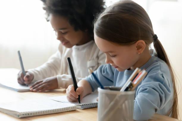 istock African and Caucasian schoolgirl mates sit at table writing task 1252896390