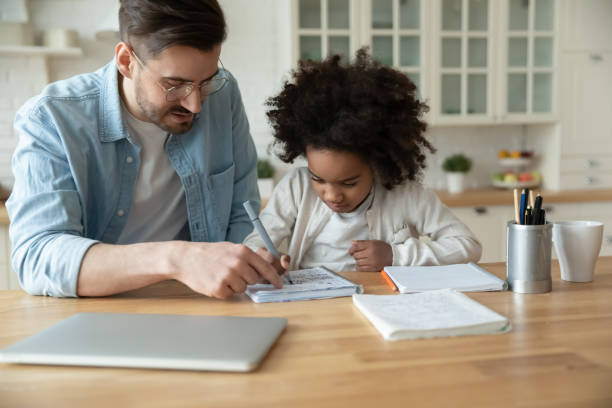caucasian stepfather helps with homework little mixed-race daughter - child thinking writing little girls imagens e fotografias de stock