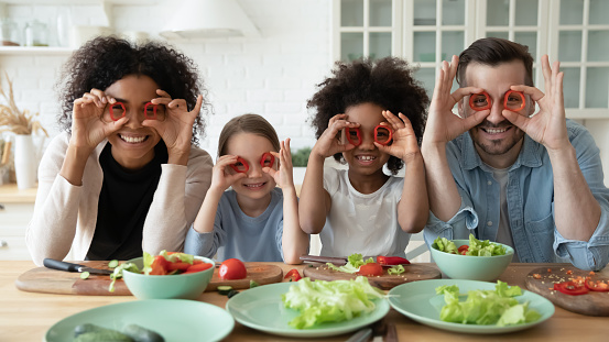Family cooking together having fun covering eyes with red paprika