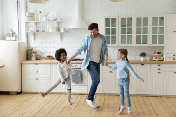 istock Caucasian father multiethnic daughters dancing in modern cozy kitchen 1252896456