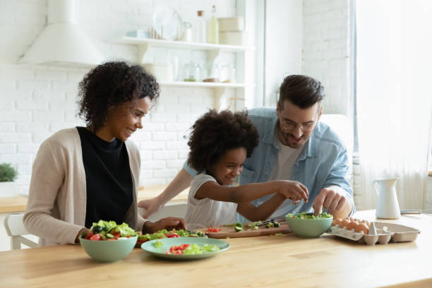istock Caring multiethnic couple teach small daughter cook vegetable salad 1252896469