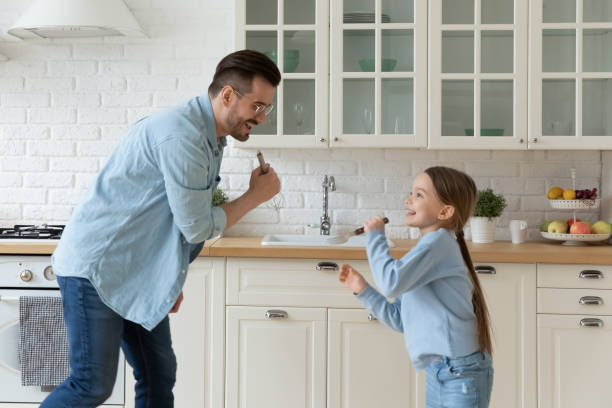 istock Dad and little daughter singing in kitchen enjoy weekend fun 1252896474