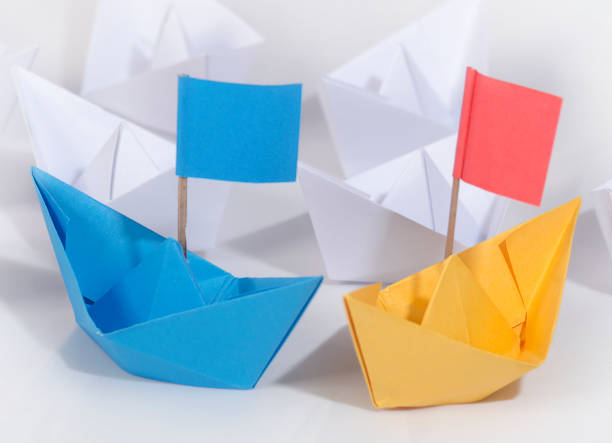 istock Business competition concept using two different color origami paper boats 1252900732