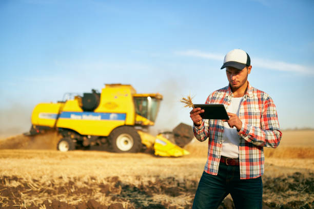 istock Precision farming. Farmer holding tablet for combine harvester guidance and control with modern automation system. Agronomist using online data management software generating yield maps at wheat field 1252901103
